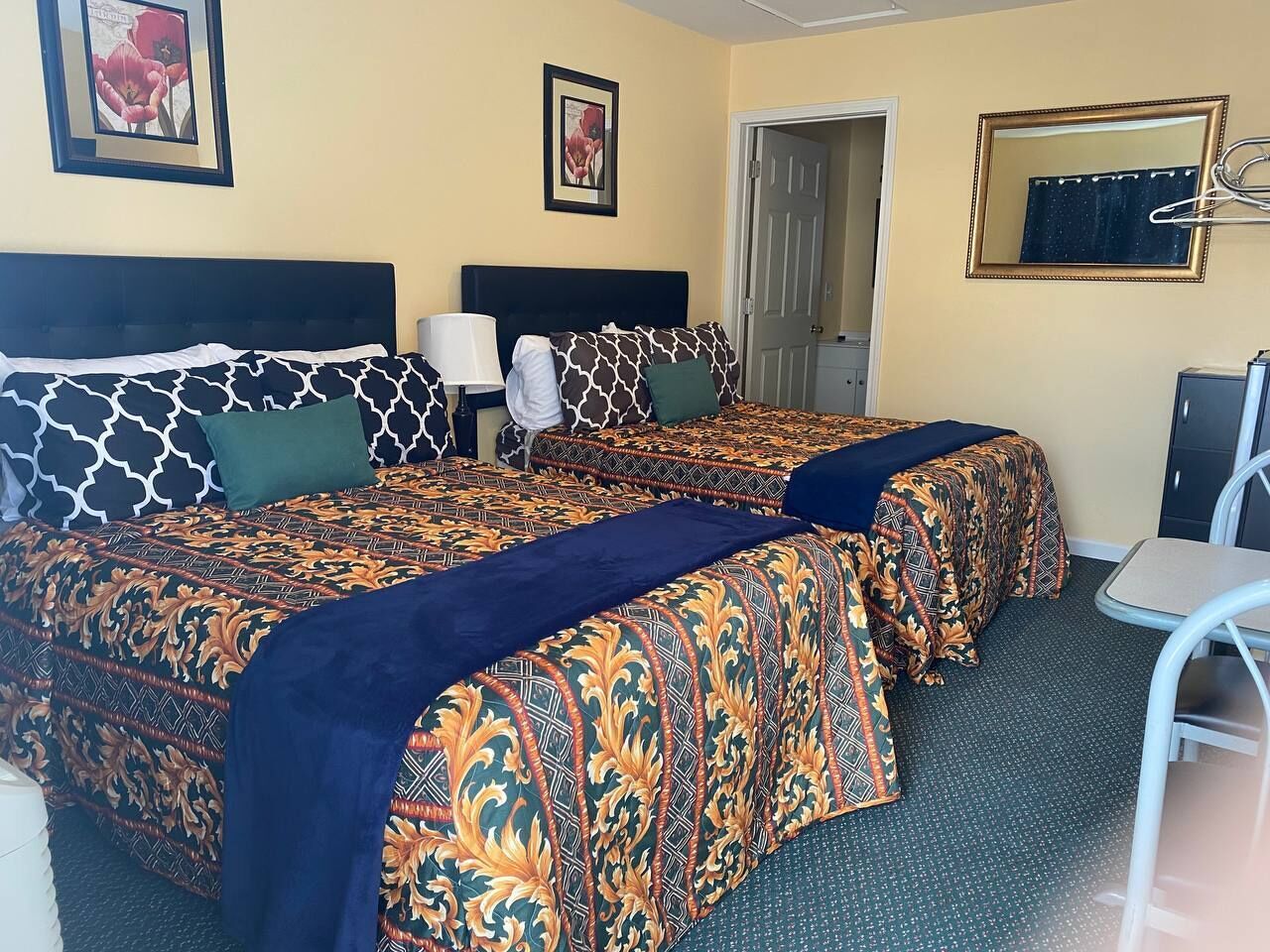 A hotel room with two beds, a desk, and a chair.