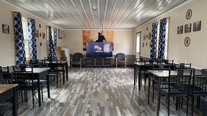 Una habitación amplia con una larga mesa en el centro, rodeada de sillas, y una pantalla grande que muestra el logotipo de Discovery+.