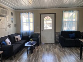 Uma sala de estar acolhedora com dois sofás, uma mesa de centro e uma porta com janela.