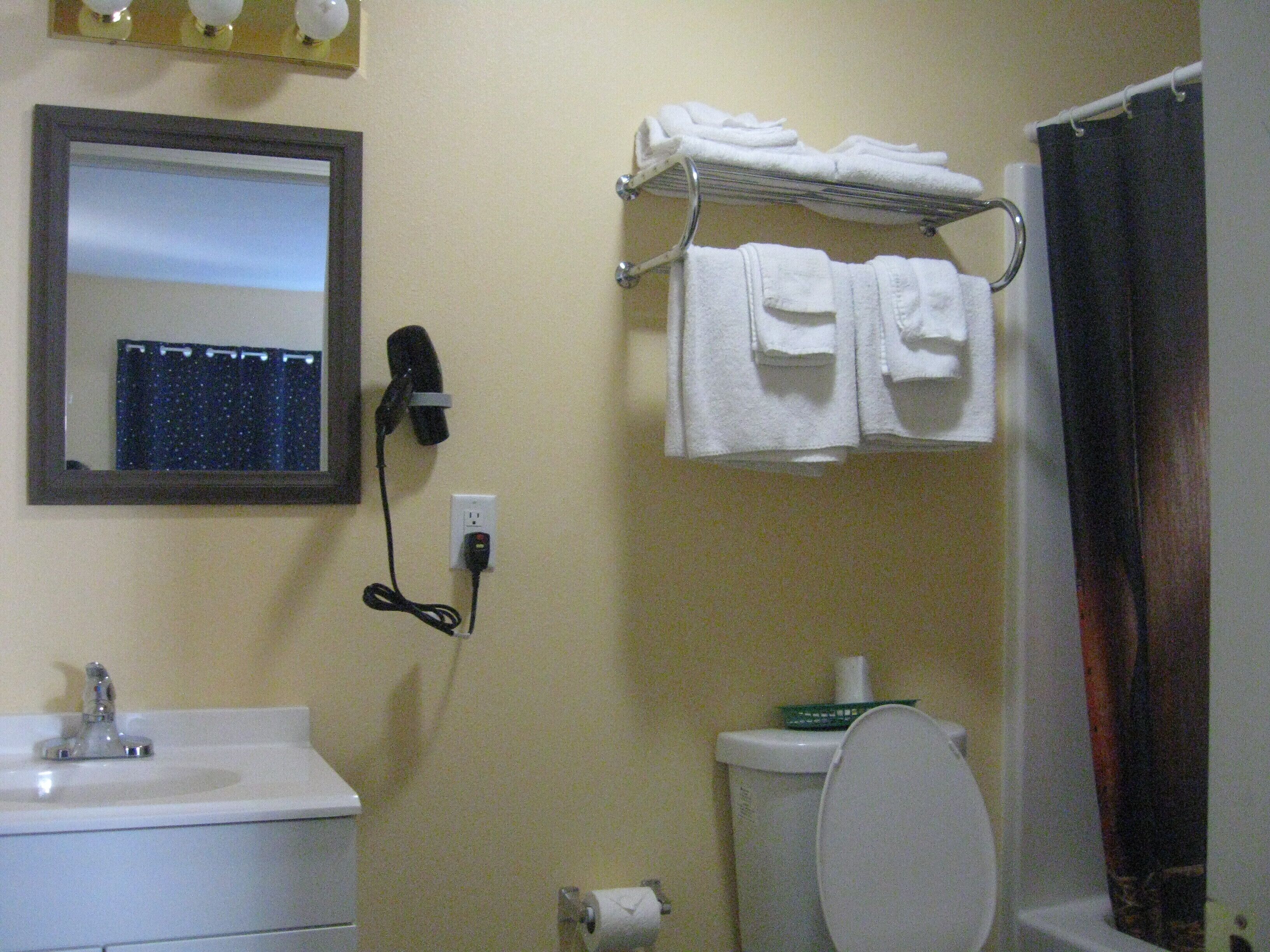 Een badkamer met een wastafel, spiegel, handdoekhouder en toilet.