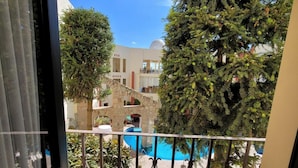 A balcony with a view of a swimming pool, a stone bridge, and a building with a dome.