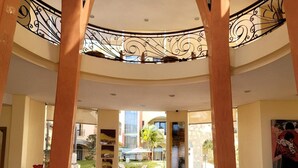 A spacious lobby with a central glass display case, a pool view, and a modern architectural design.