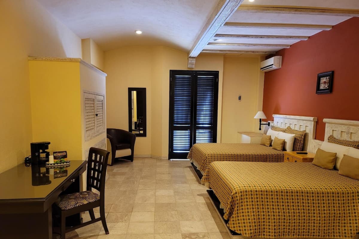 Una habitación de hotel con dos camas, un escritorio, una silla y un espejo.