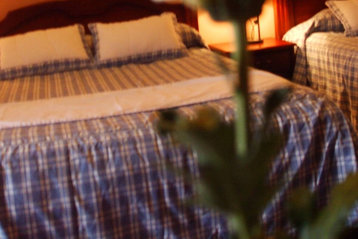 Habitación de hotel con cama, mesita de noche y pared decorada con estampado floral.