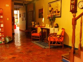 Un interior acogedor con una escalera de madera, un comedor con mesa y sillas, y una estantería.