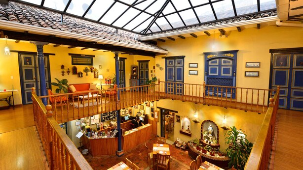 Um restaurante espaçoso, em vários níveis, com pisos de madeira e teto alto, que inclui um bar central e diversas mesas de jantar.