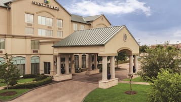 A multi-story hotel with a covered entrance and a landscaped driveway.