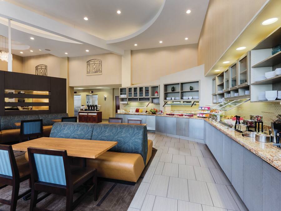 A modern restaurant with a bar area, seating, and a kitchen visible.