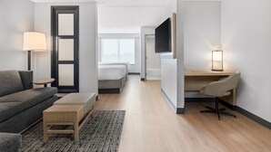 A modern hotel room with a sofa, a desk, a TV, and a bed. - Hyatt Place College Station (College Station)