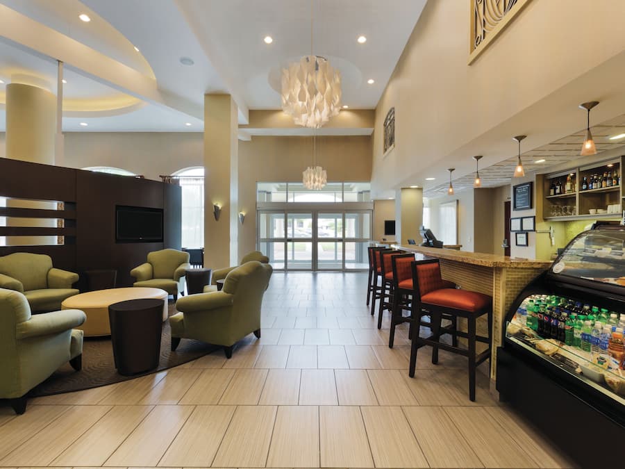 A modern hotel lobby with seating areas, a bar, and a food display.