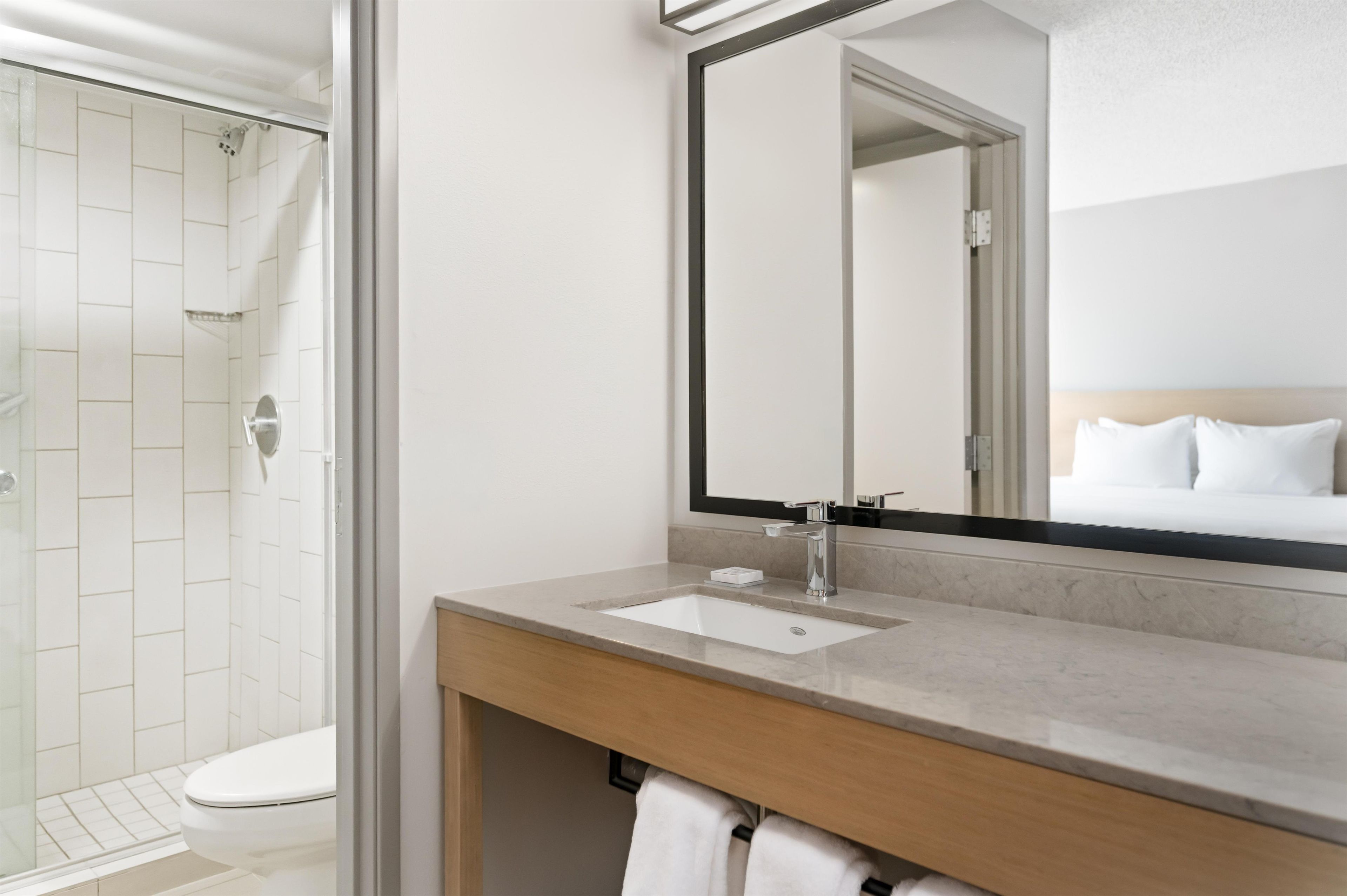 Een moderne badkamer met douche, toilet, wastafel en een grote spiegel.