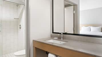 Un baño moderno con ducha, inodoro, lavabo y un espejo grande.