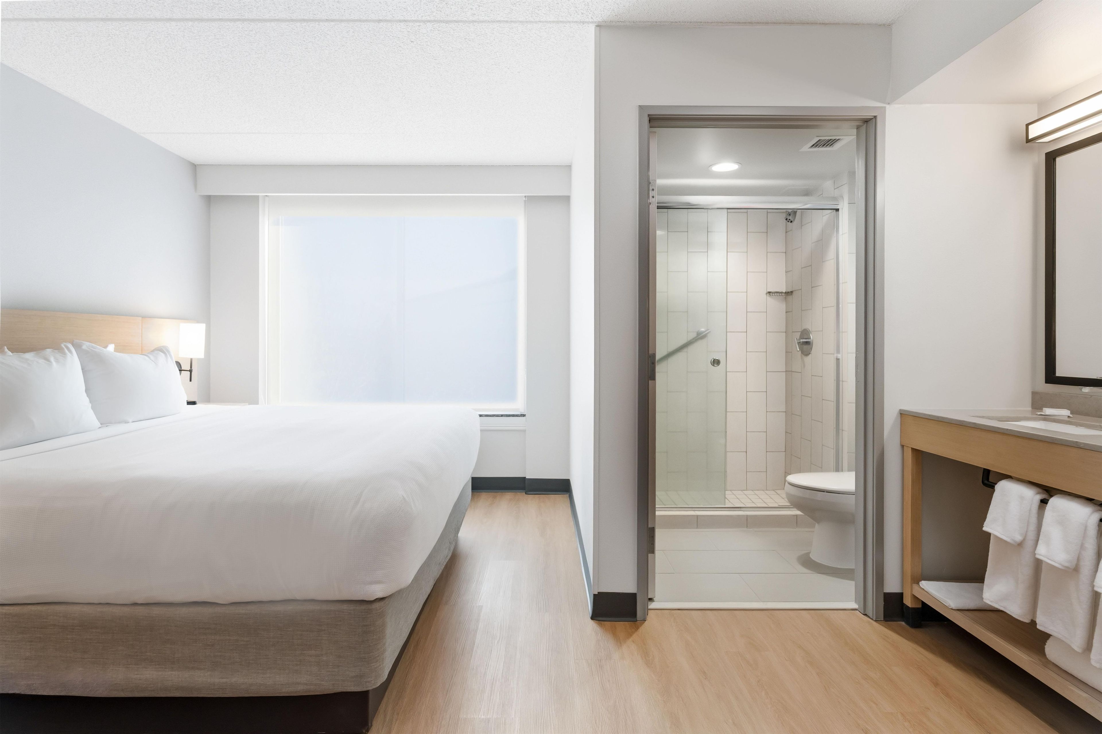 Una habitación de hotel con una cama, zona de ducha y baño con inodoro y lavabo.