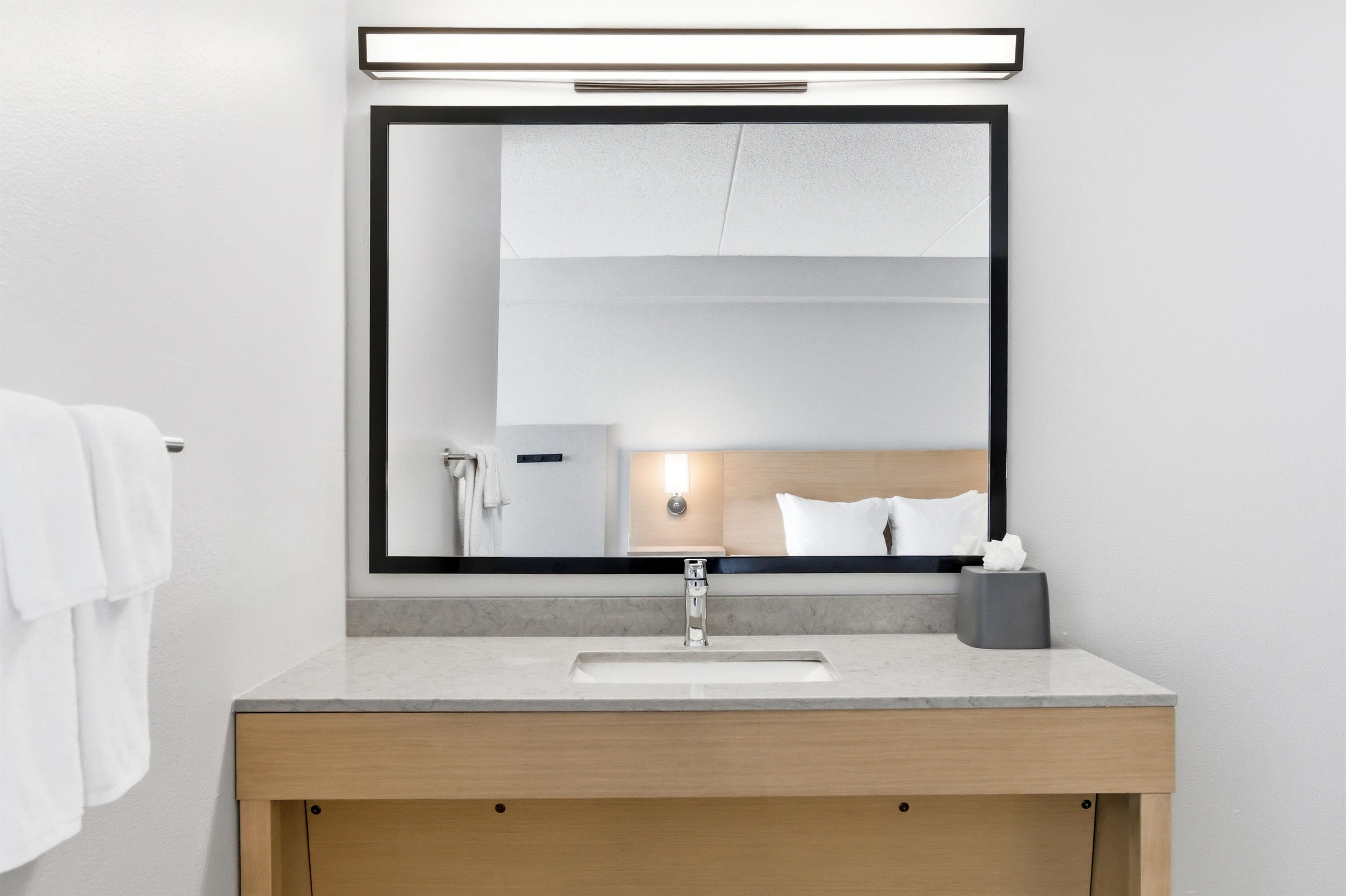 A modern bathroom with a large mirror, a sink, and a towel rack.