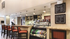 A bar area with seating, a counter, and a display case with beverages. - Hyatt Place College Station (College Station)