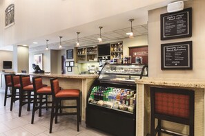 Eine Bar mit Sitzgelegenheiten, einer Theke und einer Kühlvitrine für Getränke.