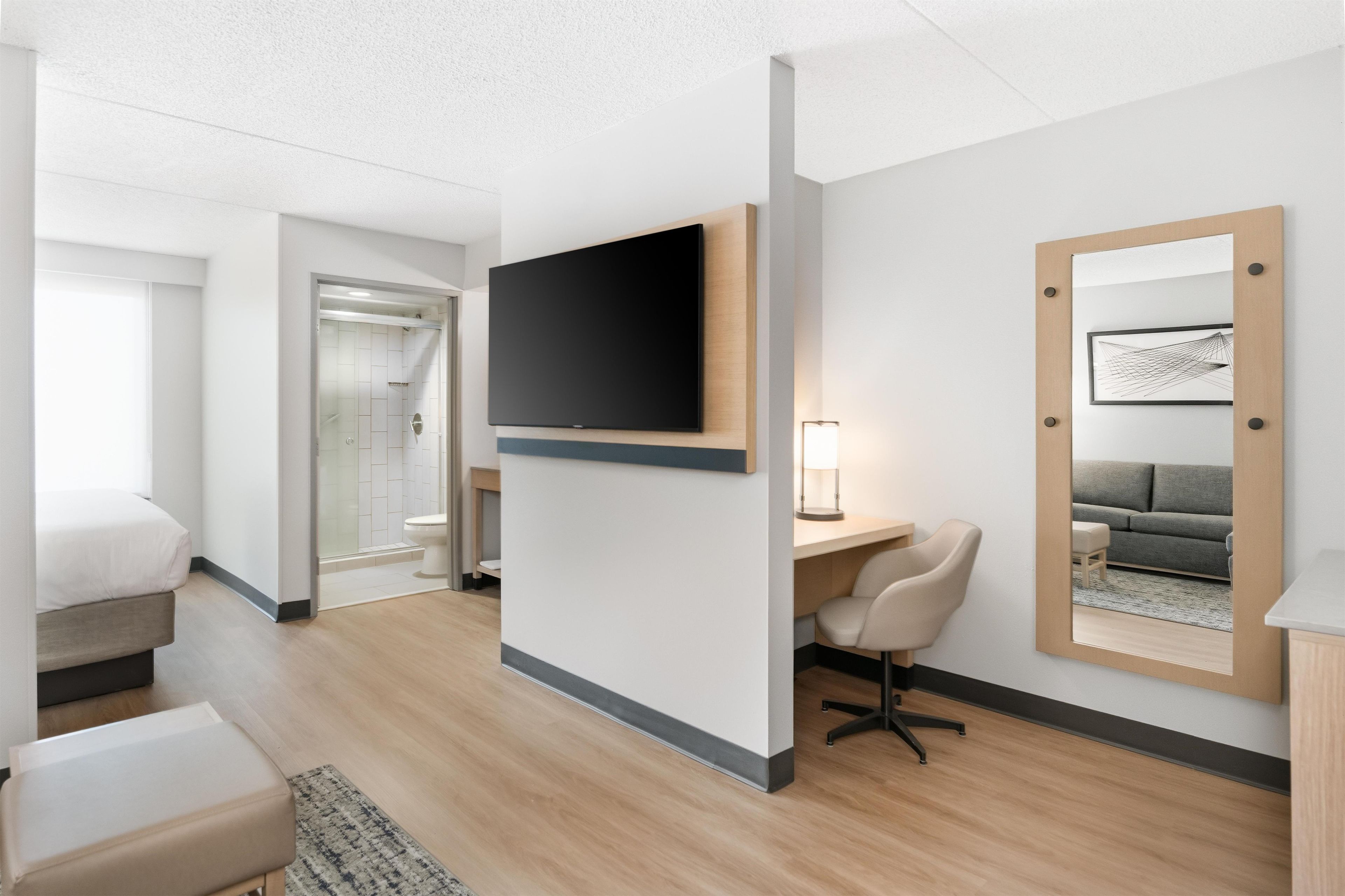 Une chambre d’hôtel équipée d’un lit, d’un bureau, d’une chaise, d’une télévision, d’un miroir et d’une salle de bain.