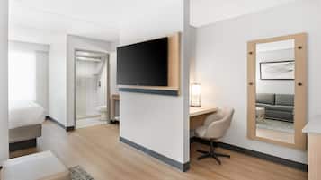 Une chambre d’hôtel équipée d’un lit, d’un bureau, d’une chaise, d’une télévision, d’un miroir et d’une salle de bain.