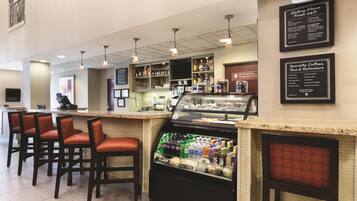 A bar area with seating, a beverage display, and a menu board.