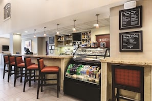 A bar area with seating, a beverage display, and a menu board. - Hyatt Place College Station (College Station)