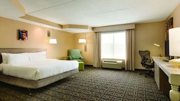 A hotel room with a large bed, a desk, a chair, and a window with curtains.