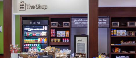 Una tienda con un letrero que dice 'The Shop', bebidas frías, aperitivos y café especial.