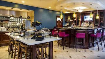 A bar area with stools, a counter, and a television screen.