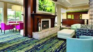 A hotel lobby with a fireplace, seating area, and a large screen displaying a nature scene. - Hilton Garden Inn Niagara-on-the-Lake (Niagara-on-the-Lake)