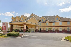 A hotel with a covered entrance, multiple windows, and a sign indicating it is part of the Best Western Plus chain.
