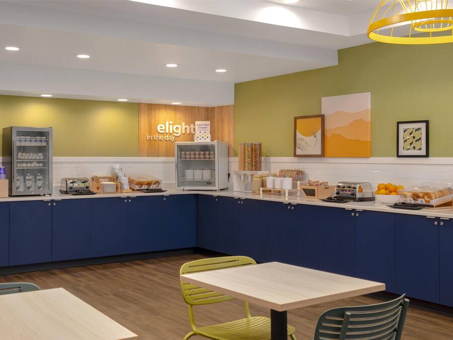 A modern kitchen with blue cabinets, a coffee machine, a bread display, and a sign that reads "elight in the day".