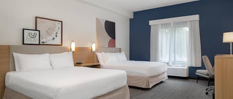 A hotel room with two beds, a desk, a chair, and a window with curtains.