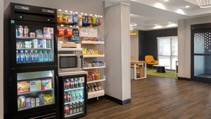 Zona de venta con diferentes aperitivos y bebidas, un microondas y un refrigerador.