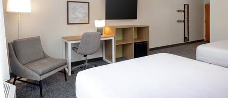Una habitación de hotel con una cama, un escritorio, una silla, un televisor y una estantería.