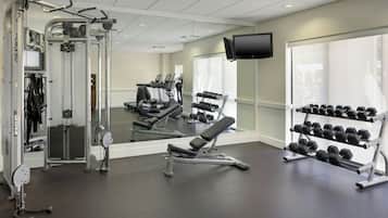 A gym with cardio machines, weightlifting equipment, and a TV mounted on the wall.