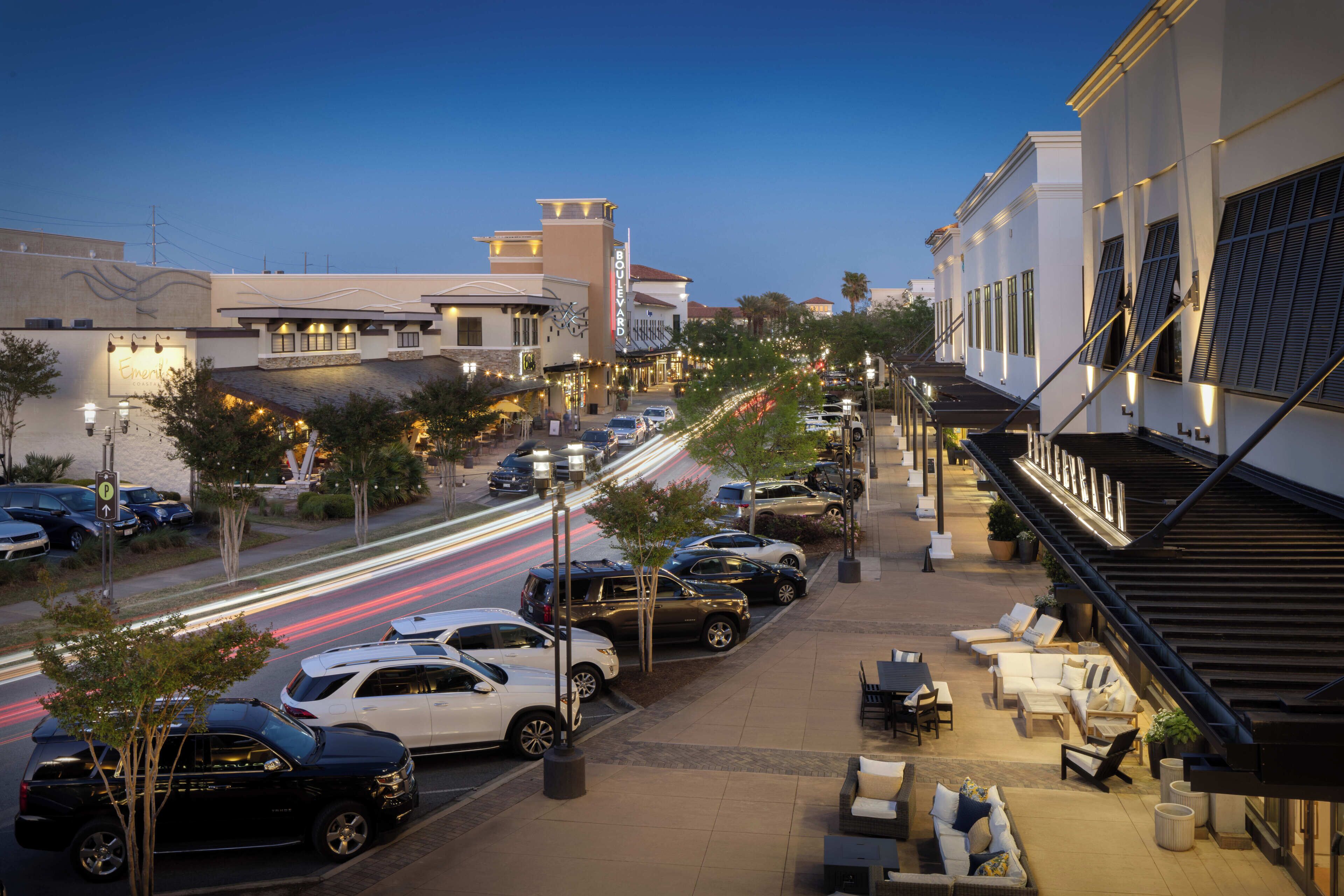 A hotel with outdoor seating, a covered walkway, and a view of the street.