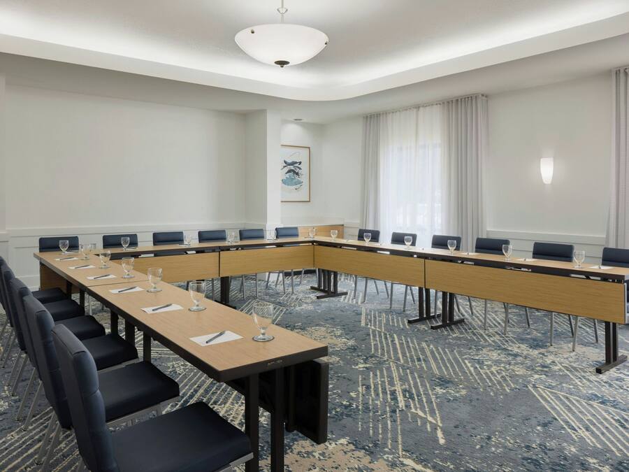 A conference room with a long table, black chairs, and a carpeted floor.