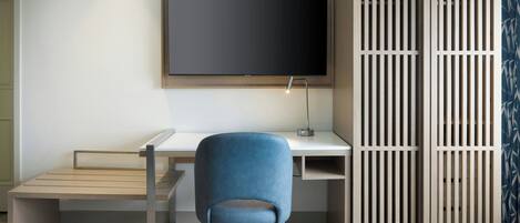 Un espacio de oficina moderno con un escritorio, una silla y una pantalla de televisión grande.