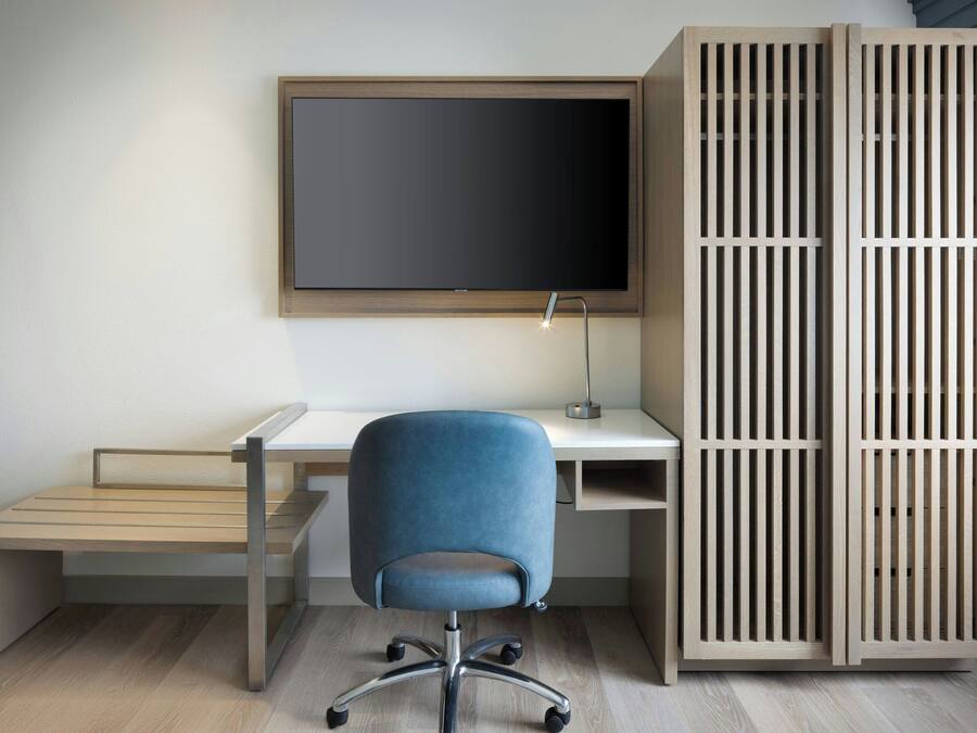 A modern office space with a desk, chair, and a large TV screen.