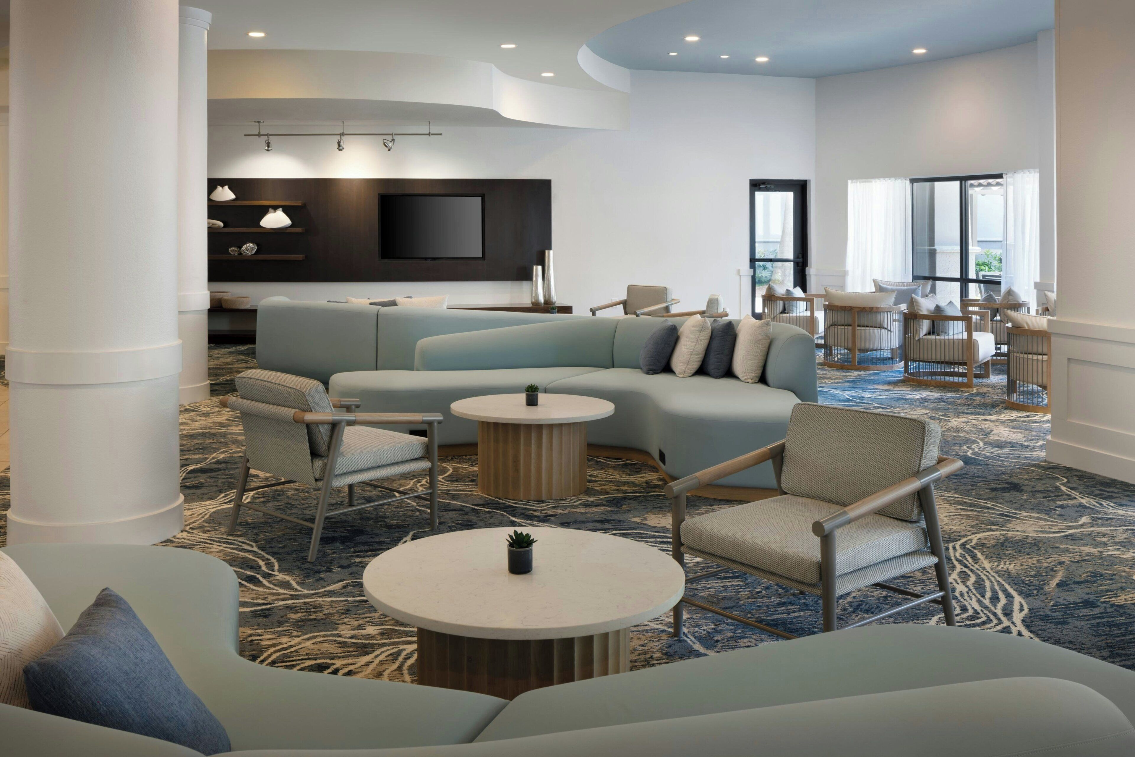 A modern lounge area with a sectional sofa, armchairs, and a coffee table.