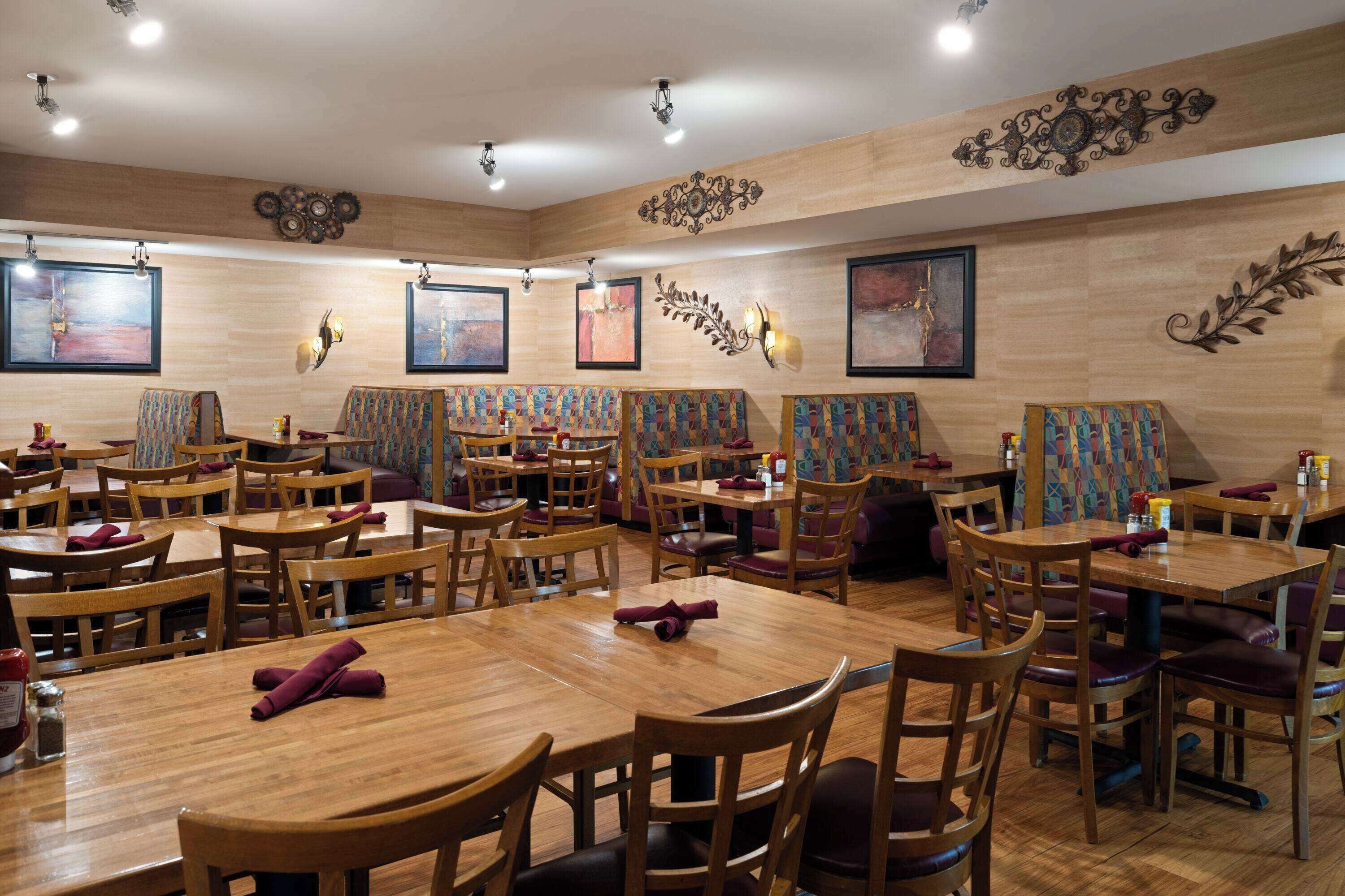 A restaurant with wooden tables and chairs, artwork on the walls, and a warm ambiance.