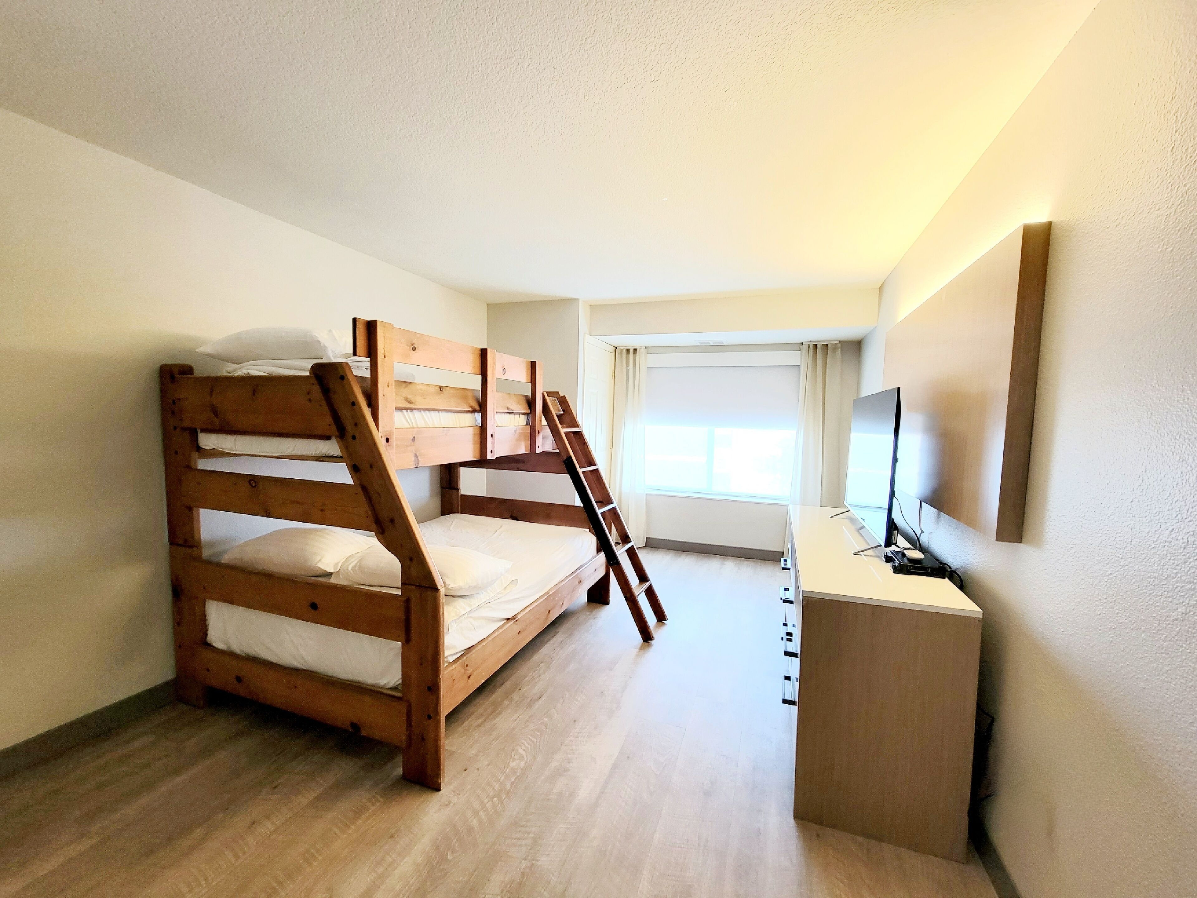 Ein Zimmer mit Etagenbett, Schreibtisch, Stuhl und Fernseher.