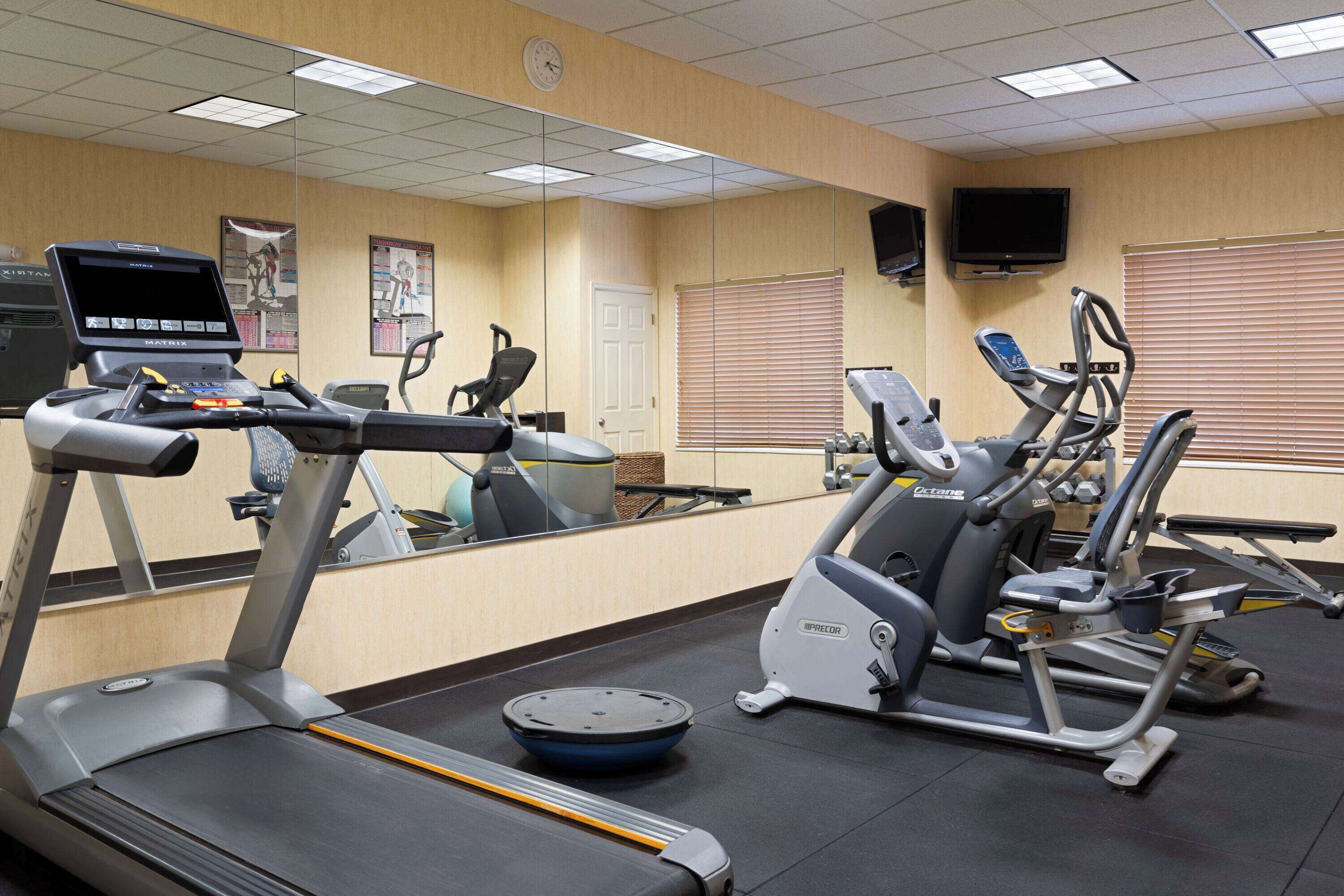 A gym with treadmills, elliptical machines, and a stationary bike.