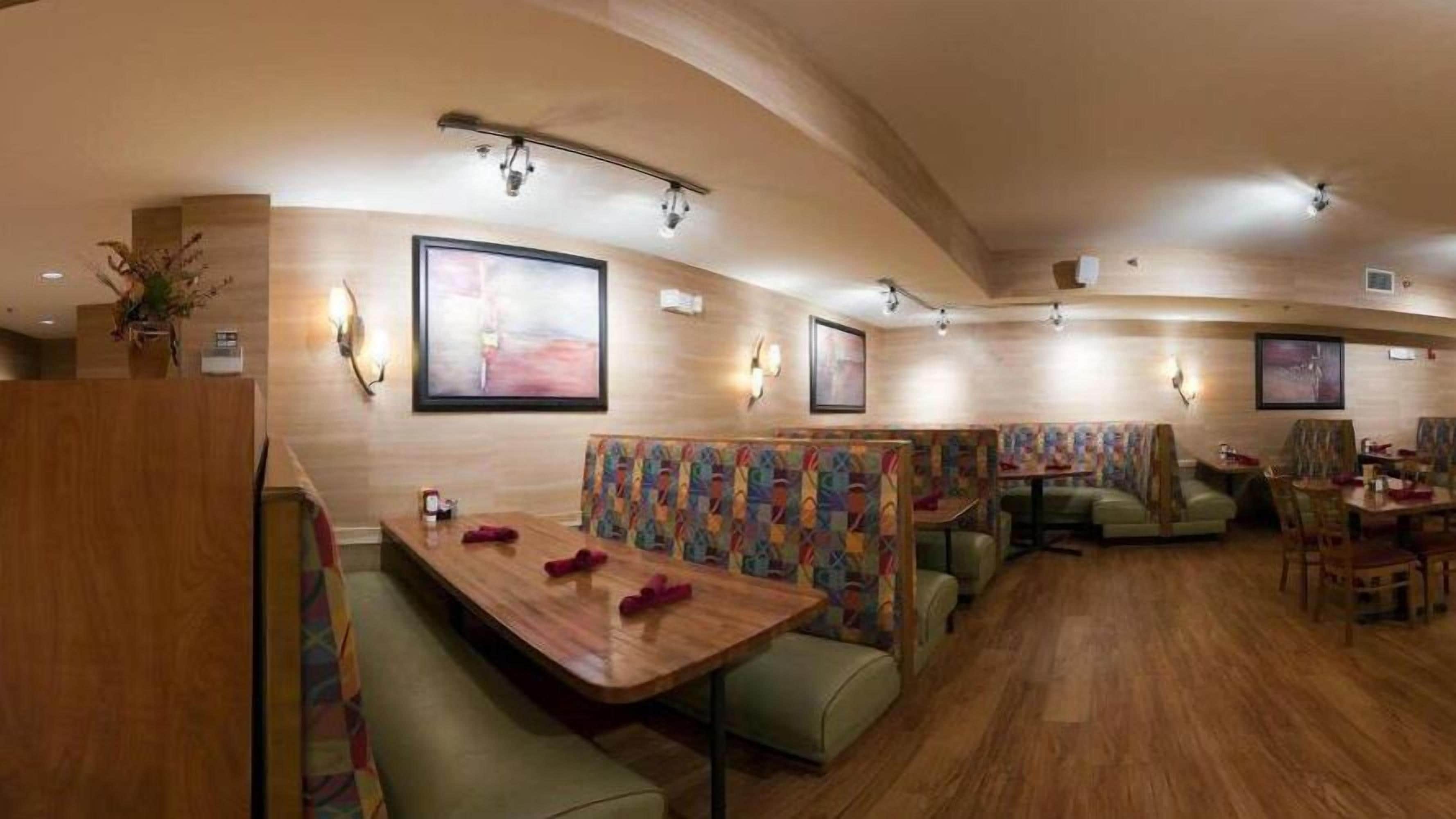 A restaurant with booths and tables, wooden flooring, and wall-mounted artwork.