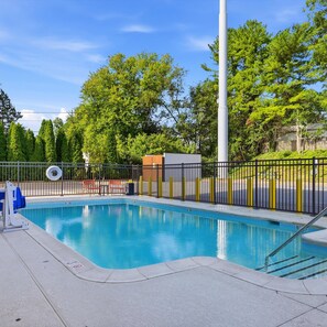 A swimming pool with a metal fence, a lifeguard stand, and a bench. - Hampton Inn Martinsburg South-Inwood (Inwood)