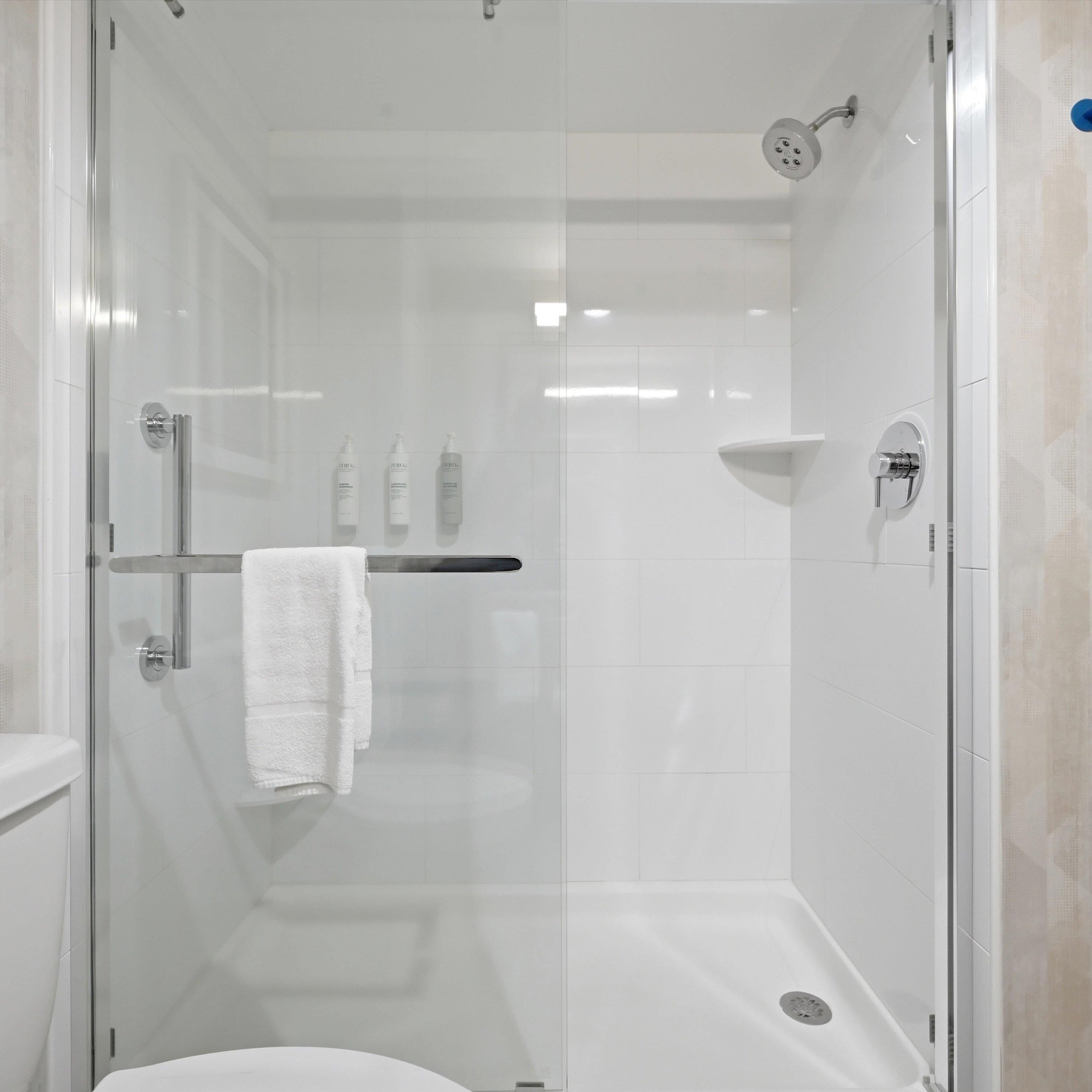 A modern bathroom with a glass-enclosed shower, a white towel on a rack, and a visible toilet.