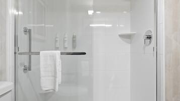 A modern bathroom with a glass-enclosed shower, a white towel on a rack, and a visible toilet.