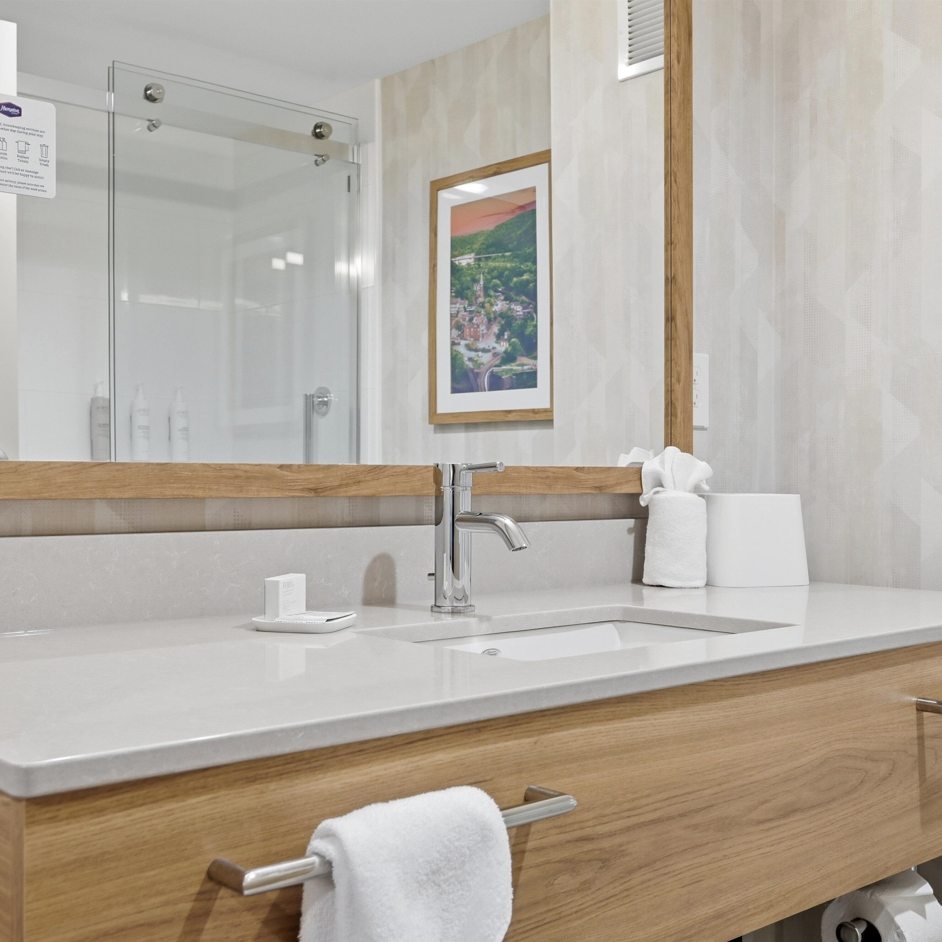 Un baño moderno con un espejo grande, un lavabo y un perchero para toallas.