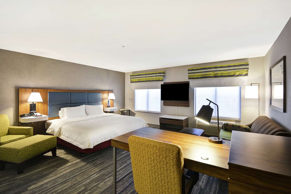 Ein Hotelzimmer mit Bett, Schreibtisch, Stuhl, Fernseher und Fenster.