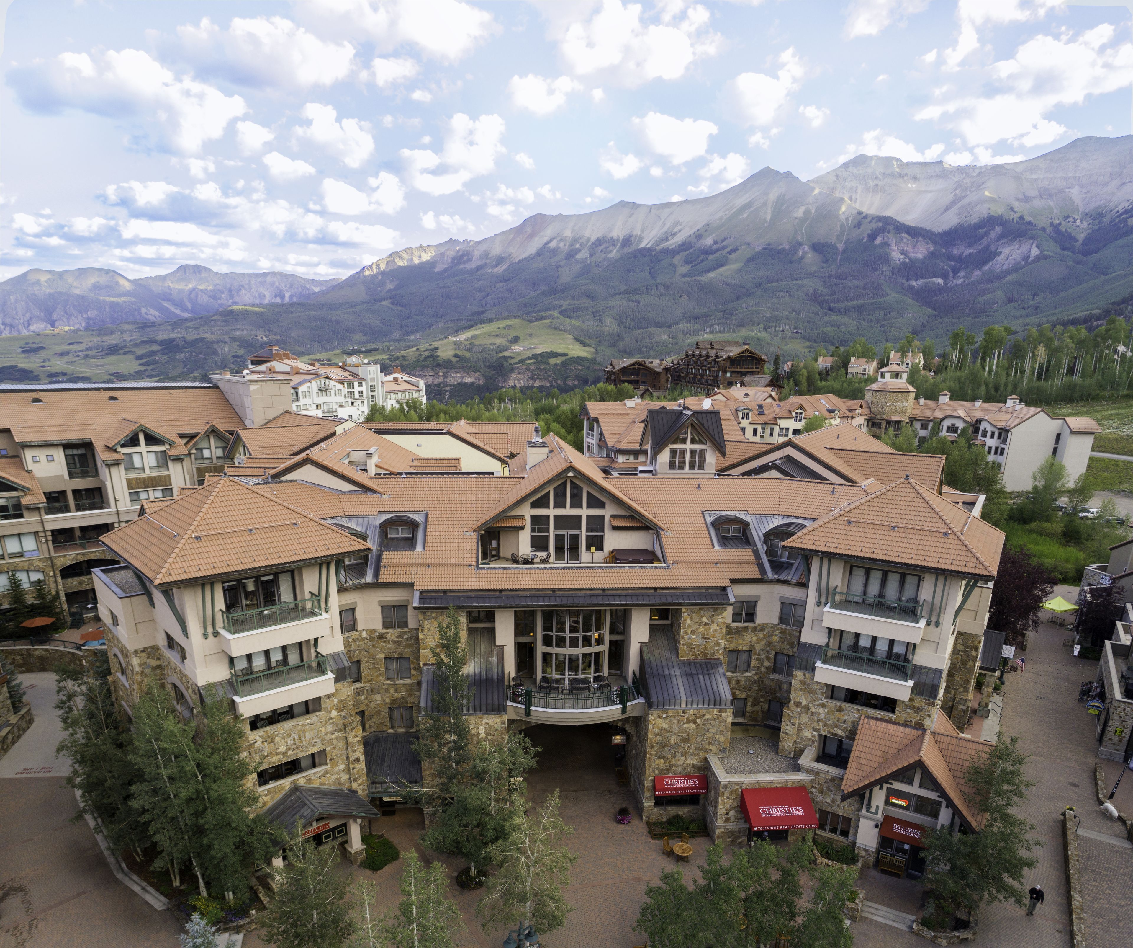 A resort with multiple buildings, a central courtyard, and mountainous views in the background.