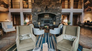 A spacious lobby with a stone fireplace, comfortable seating, and a chandelier. - Fairmont Heritage Place, Franz Klammer Lodge (Telluride)